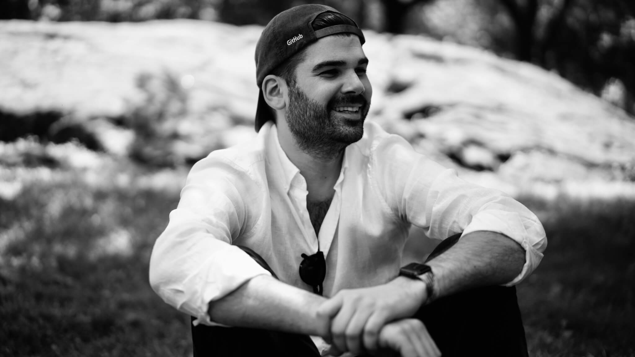 Stefan sitting in a park with a GitHub cap on